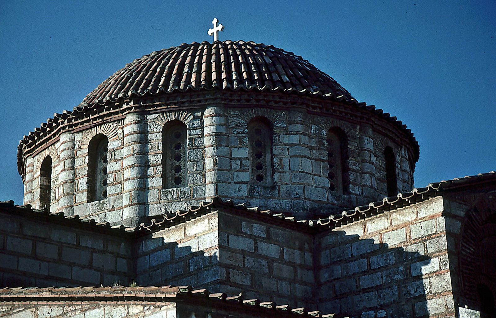 The drum and dome of Daphni Monastery, cloisonné masonry against a blue sky