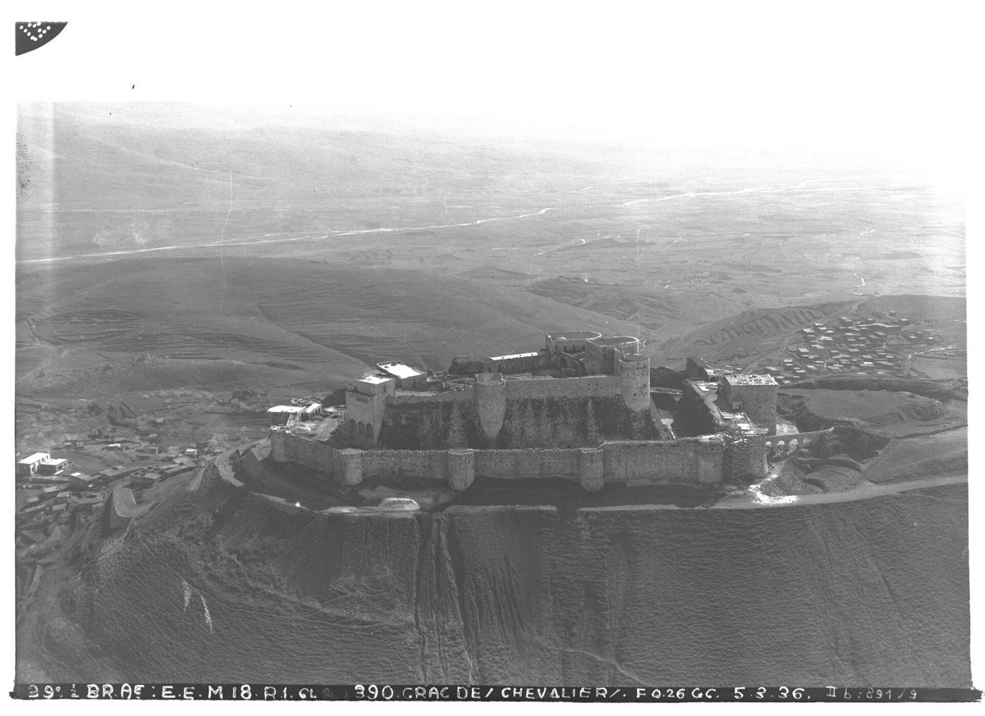 Aerial view of Krak des Chevaliers: two concentric circuits of walls and towers wrapped around a Syrian hilltop
