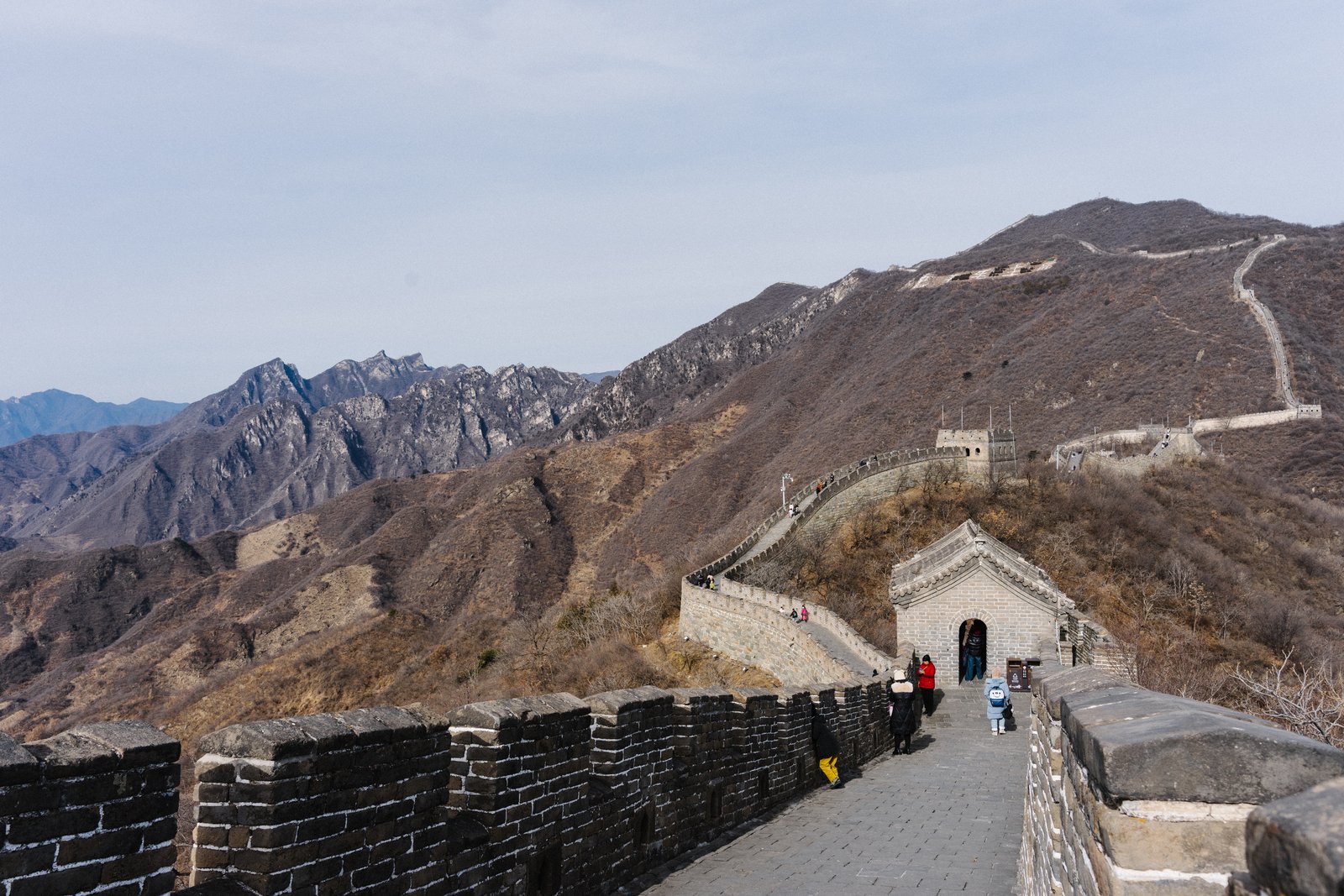 The Great Wall at Mutianyu winding over forested ridges, with a watchtower in the foreground