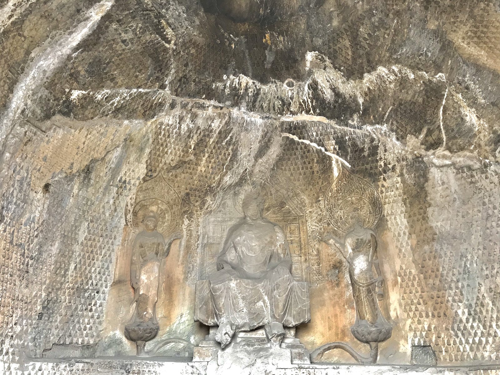 A great carved Buddha with attendant figures in a grotto at Longmen, Luoyang