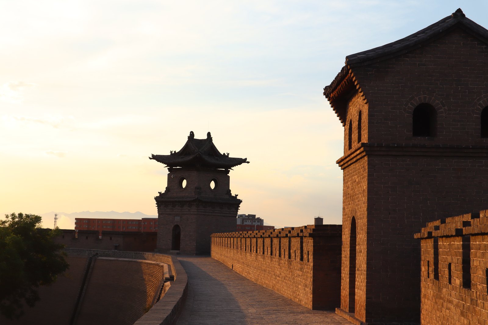 The old city wall of Pingyao at sunset, with a watchtower and gate tower