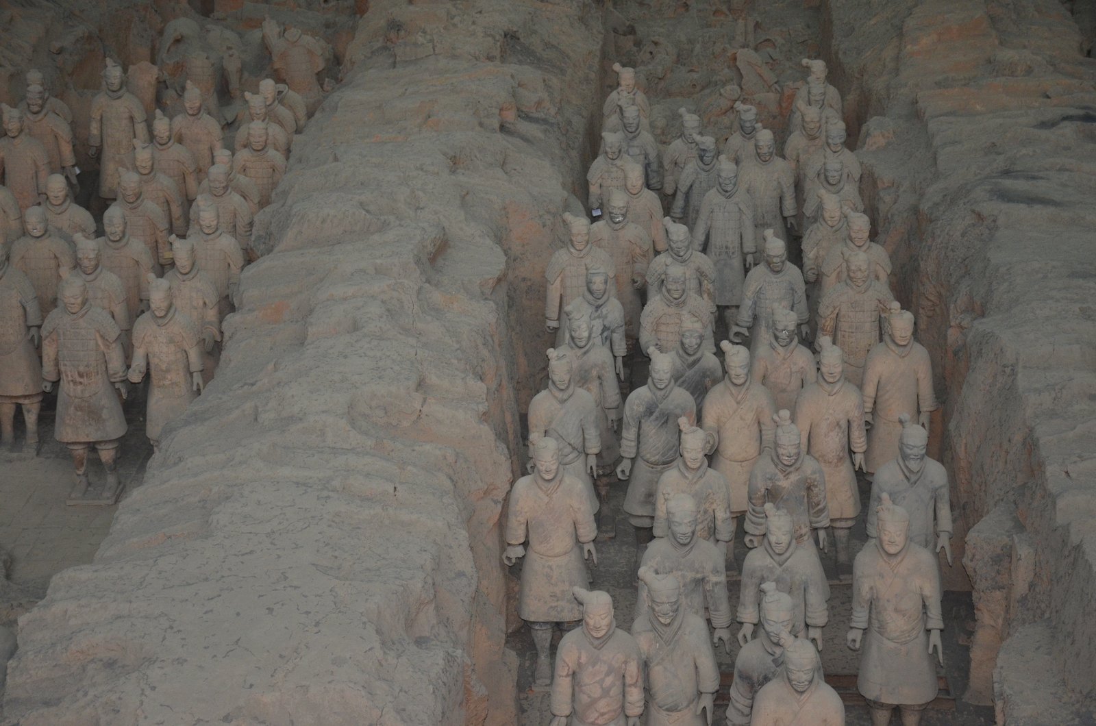 Rows of terracotta warriors standing in their excavation pit corridors at Xi'an