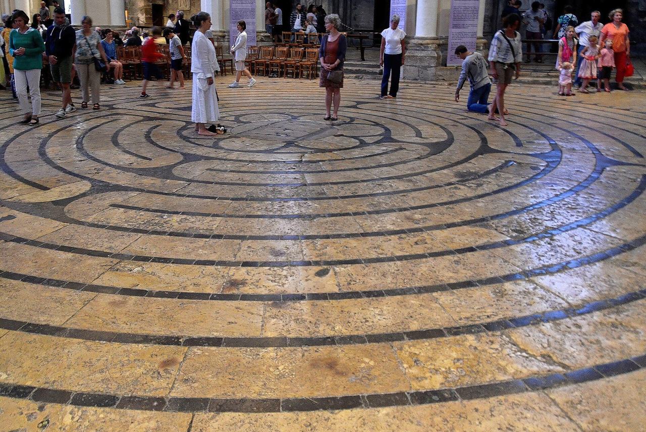The stone labyrinth set into the nave floor of Chartres Cathedral, walked by visitors