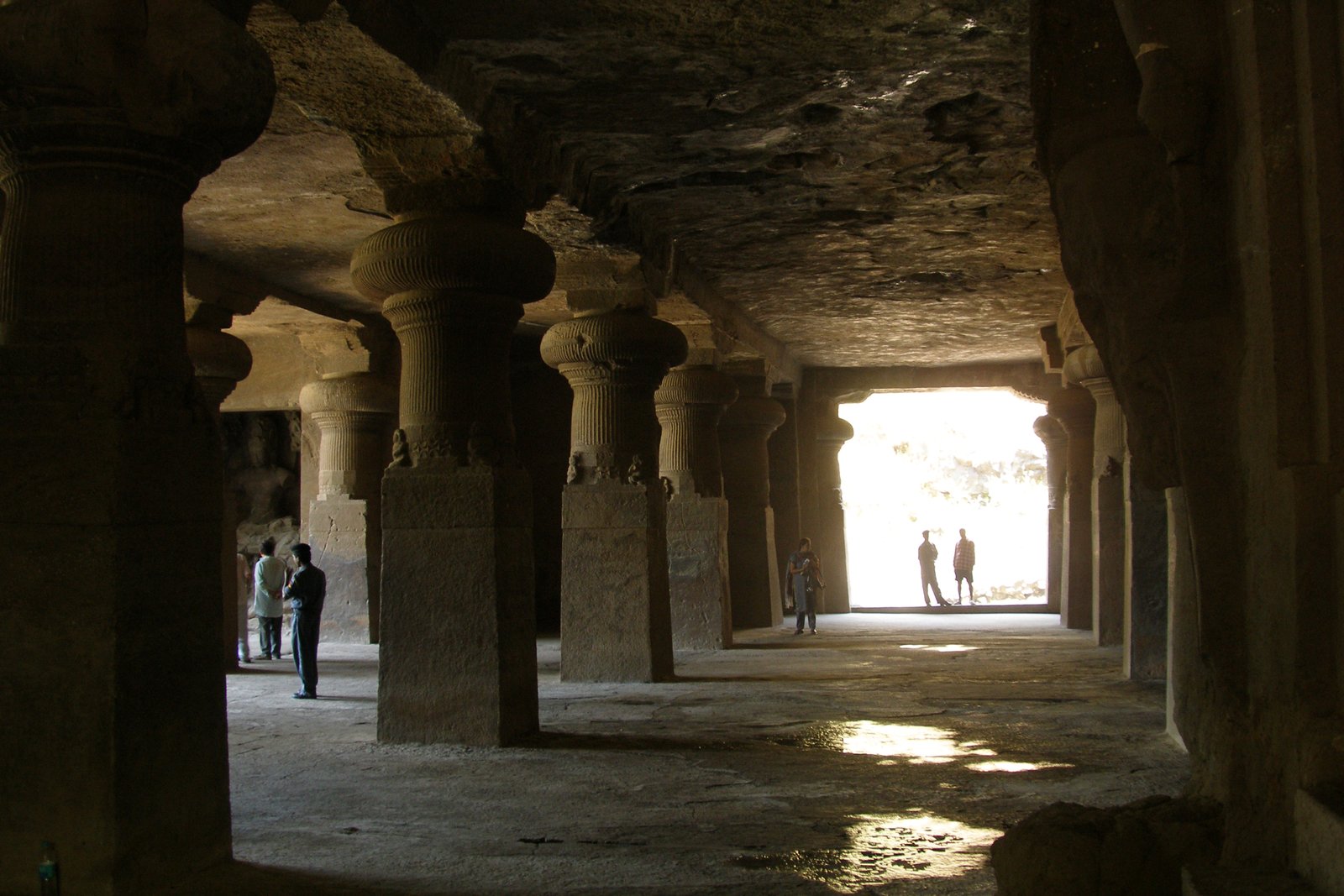 Inside the Elephanta Caves, massive rock-cut columns leading to the light of the entrance