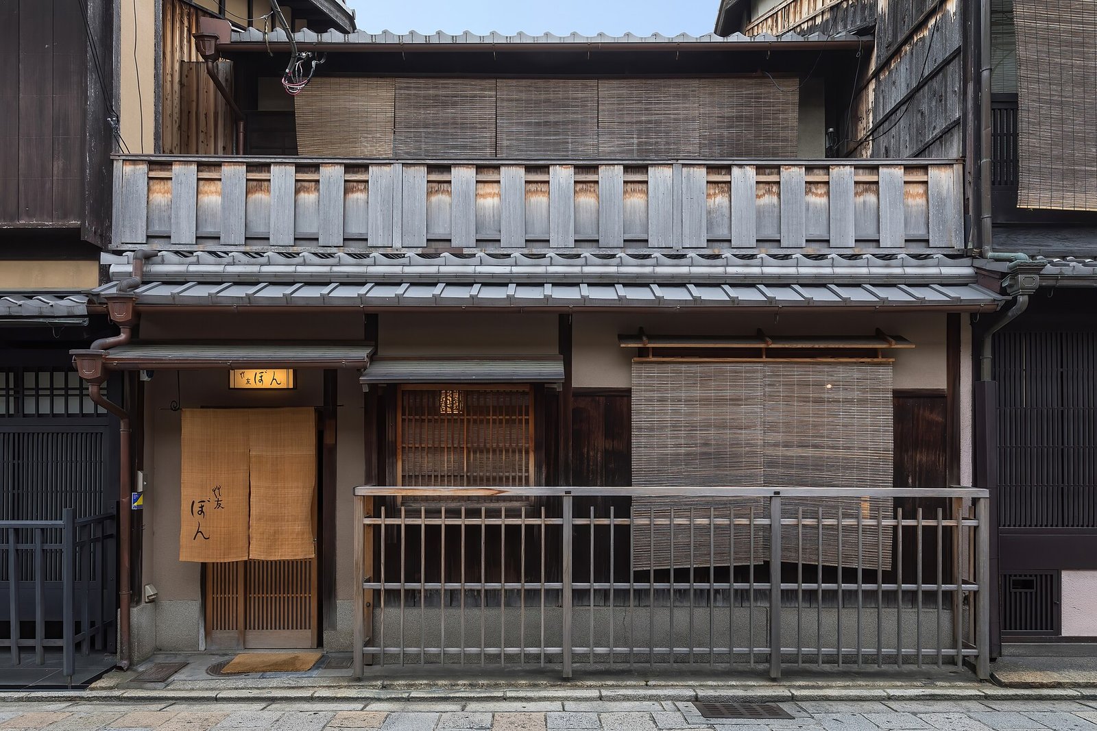 A machiya facade in Kyoto, with timber lattice, sudare blinds and a noren curtain