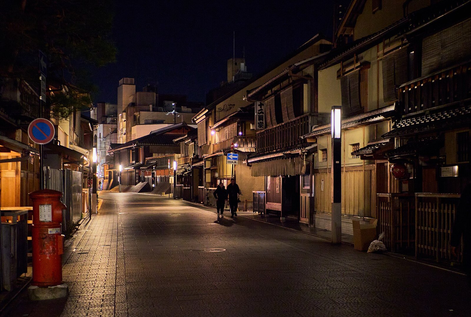 Gion at night in Kyoto, its machiya fronts lit by lamps along a quiet street