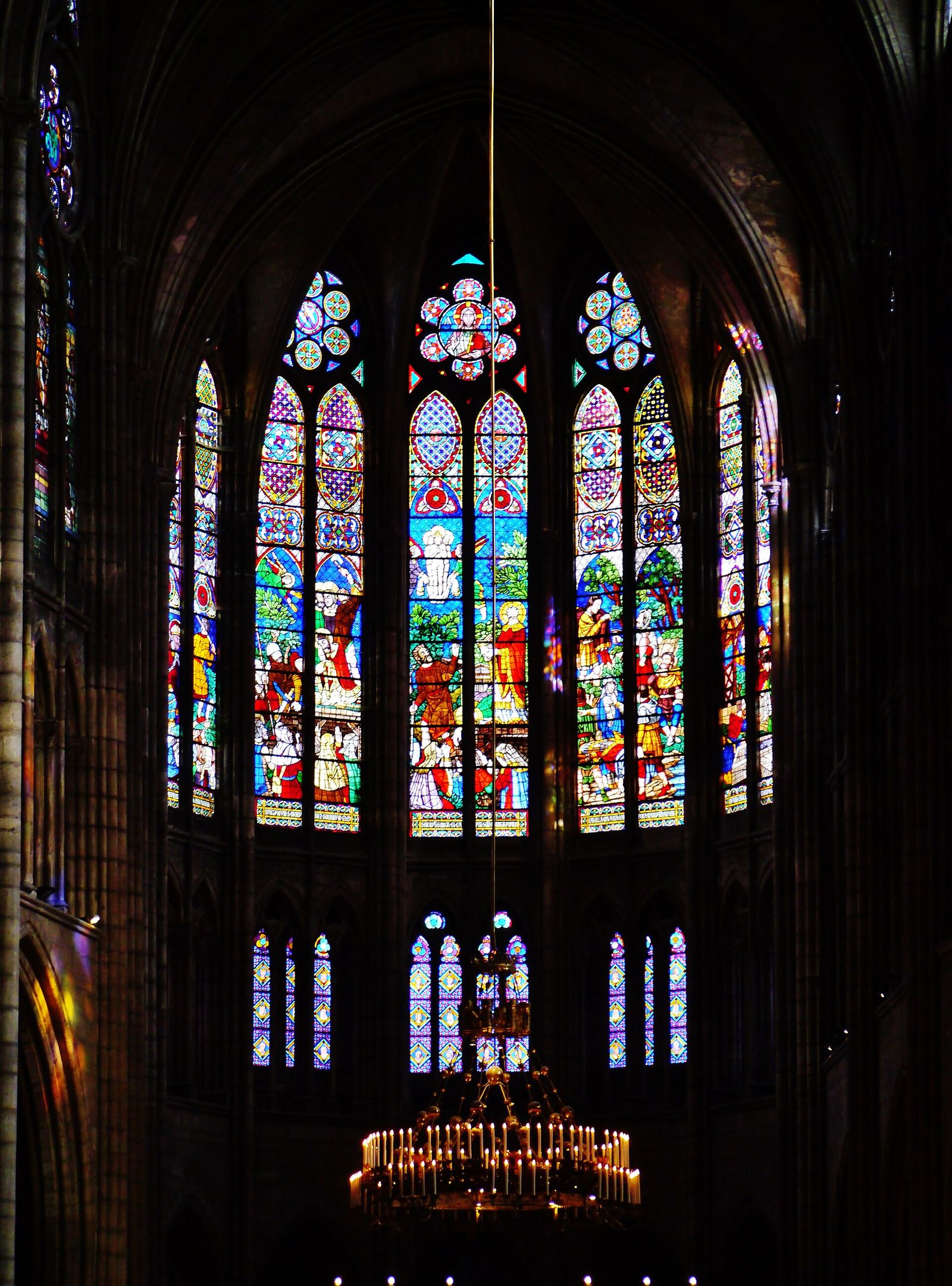 Stained-glass windows of the choir of Saint-Denis glowing against the dark interior