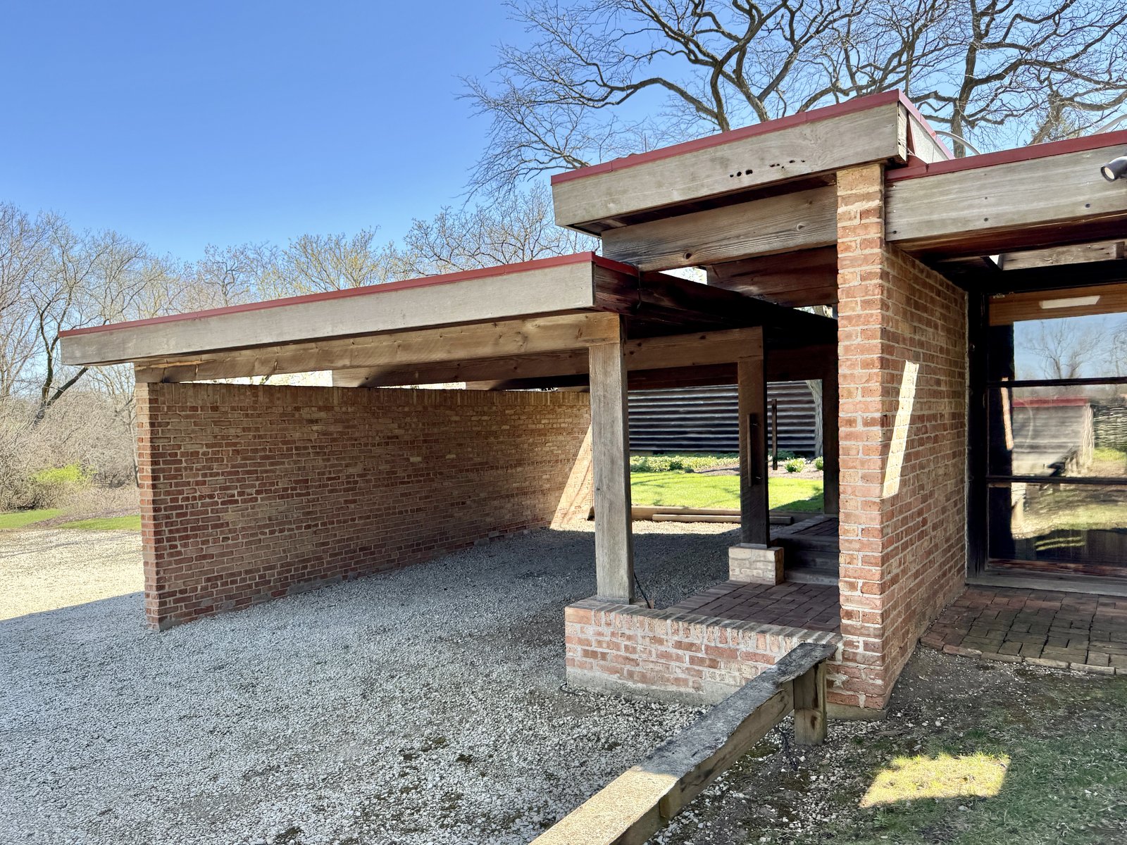 A carport beside a mid-century modern house, its flat roof on slender posts