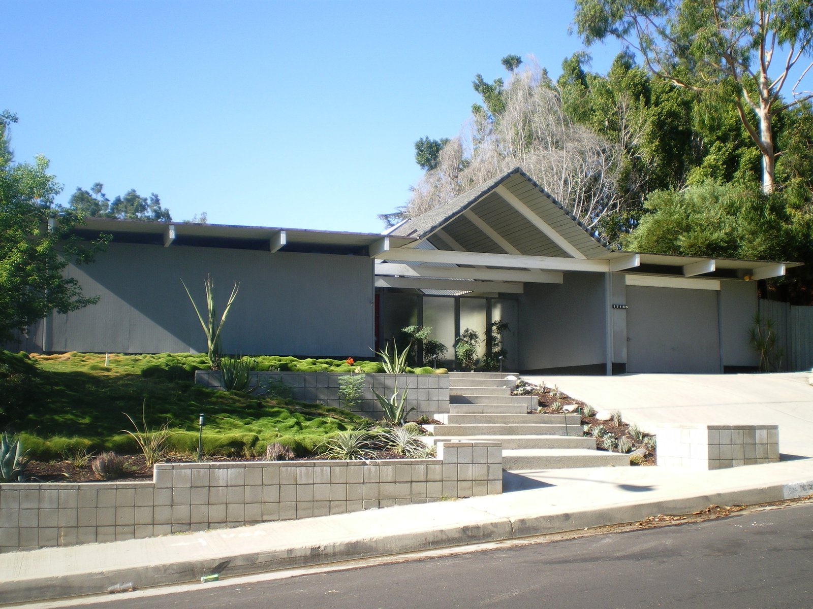 An Eichler tract home, its low flat roof, glass wall and carport facing the street