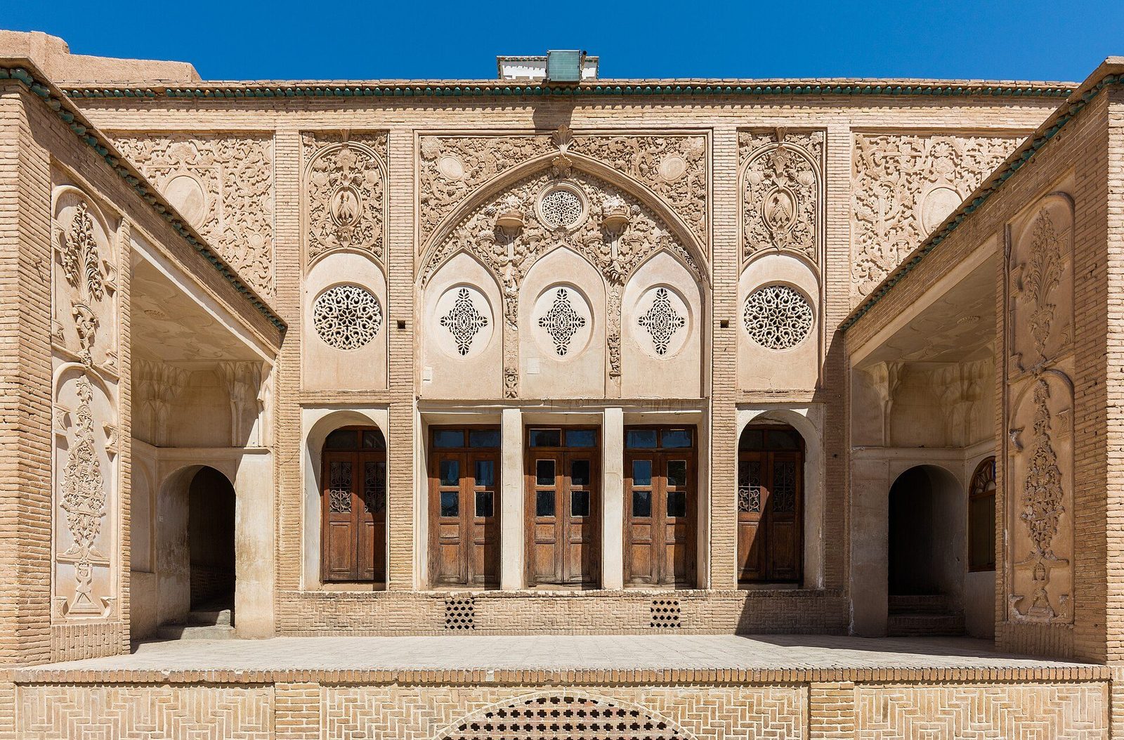 The courtyard facade of the Borujerdi House in Kashan: carved stucco, wooden screens and the house's tall doorways