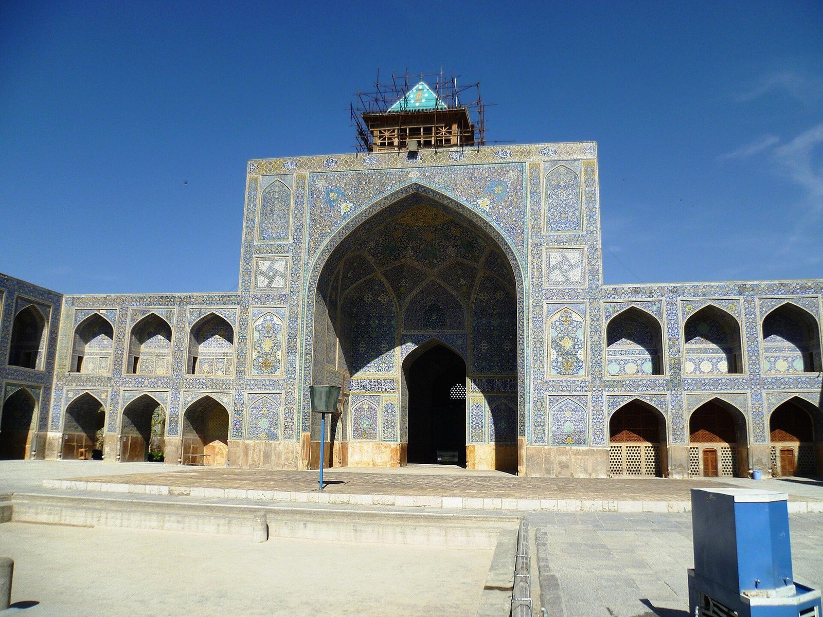 The courtyard iwan of the Shah Mosque in Isfahan, its pishtaq and flanking arcades covered in blue tile mosaic