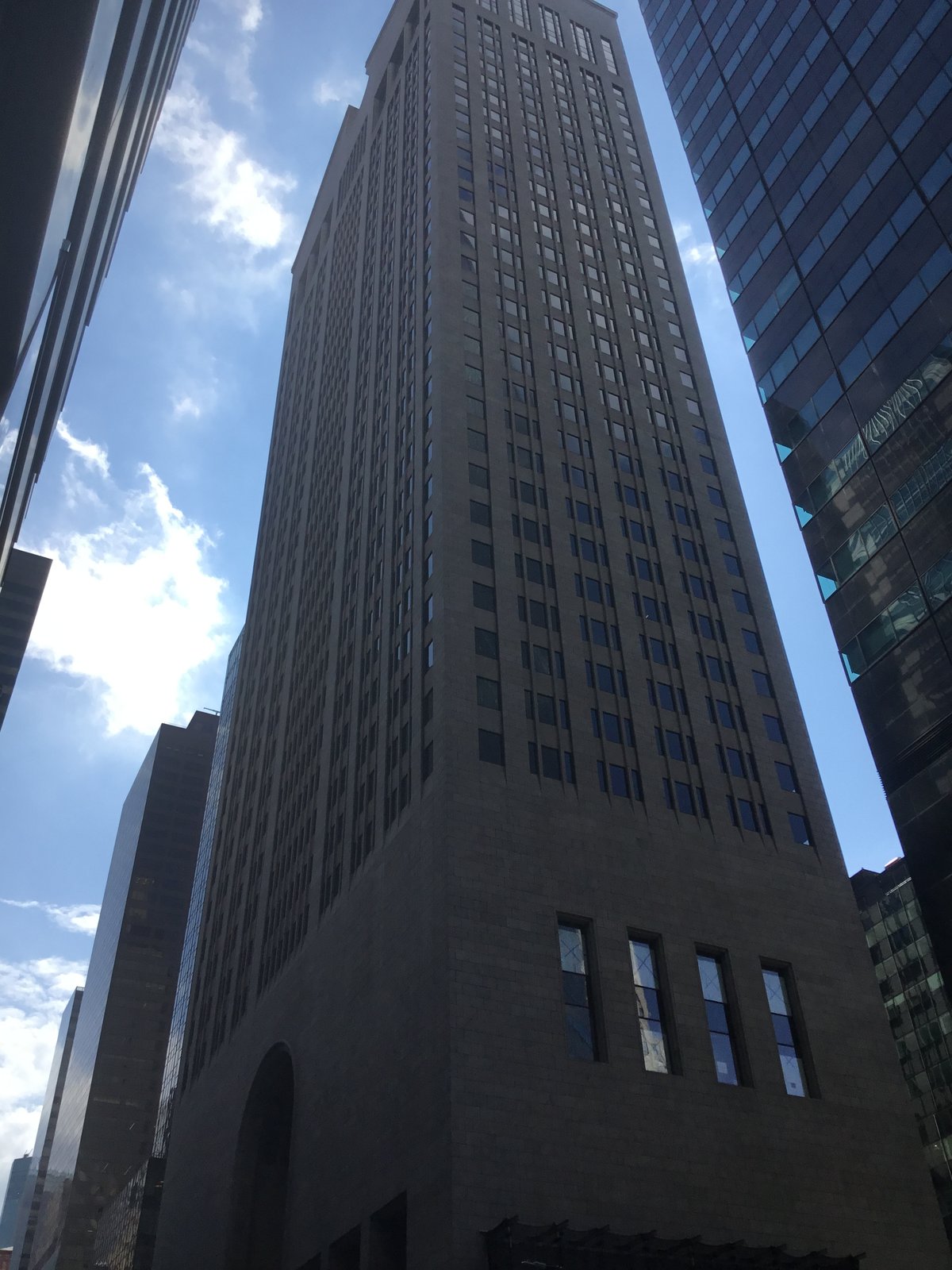 The 550 Madison Avenue tower in New York seen from street level, its dark granite shaft rising between neighbouring buildings.