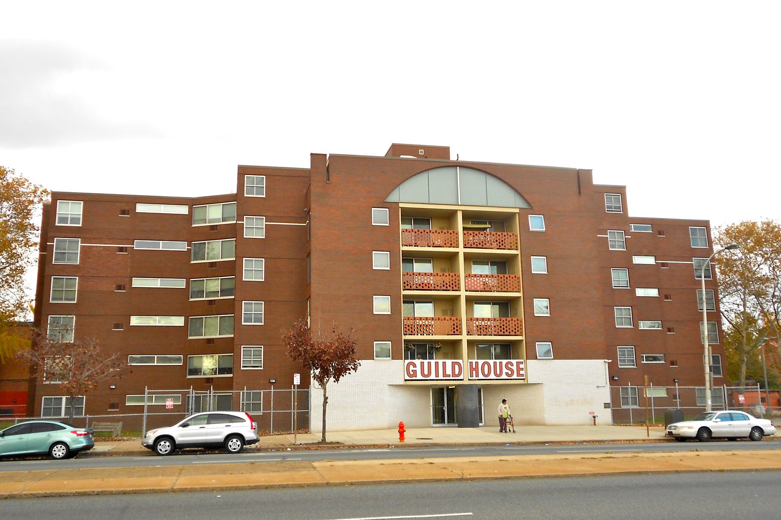 Guild House in Philadelphia, a brick apartment block with a large arched window over its entrance and a Guild House sign.