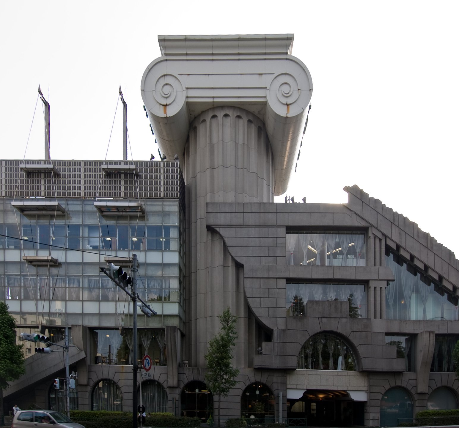 The M2 Building in Tokyo, dominated by a giant grey Ionic column and capital rising above its glass facade.