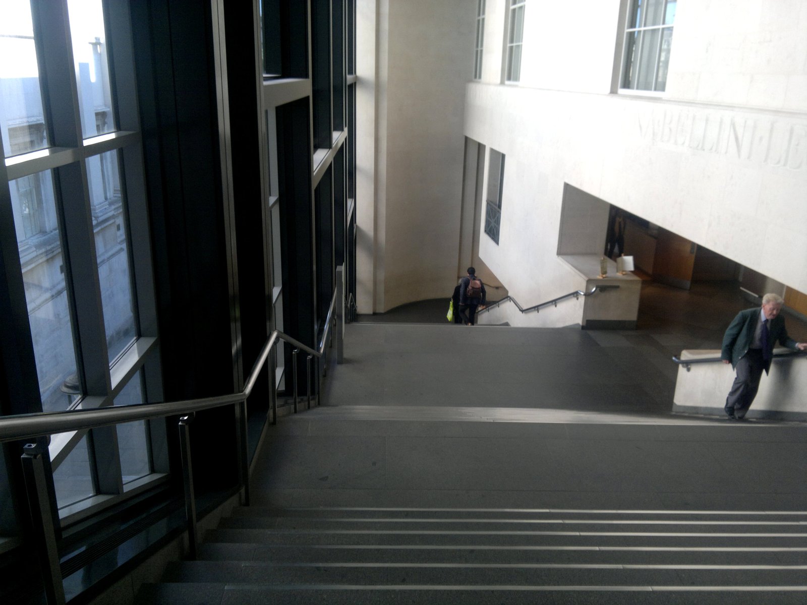 The staircase hall inside the Sainsbury Wing of the National Gallery in London, with tall windows and pale stone walls.