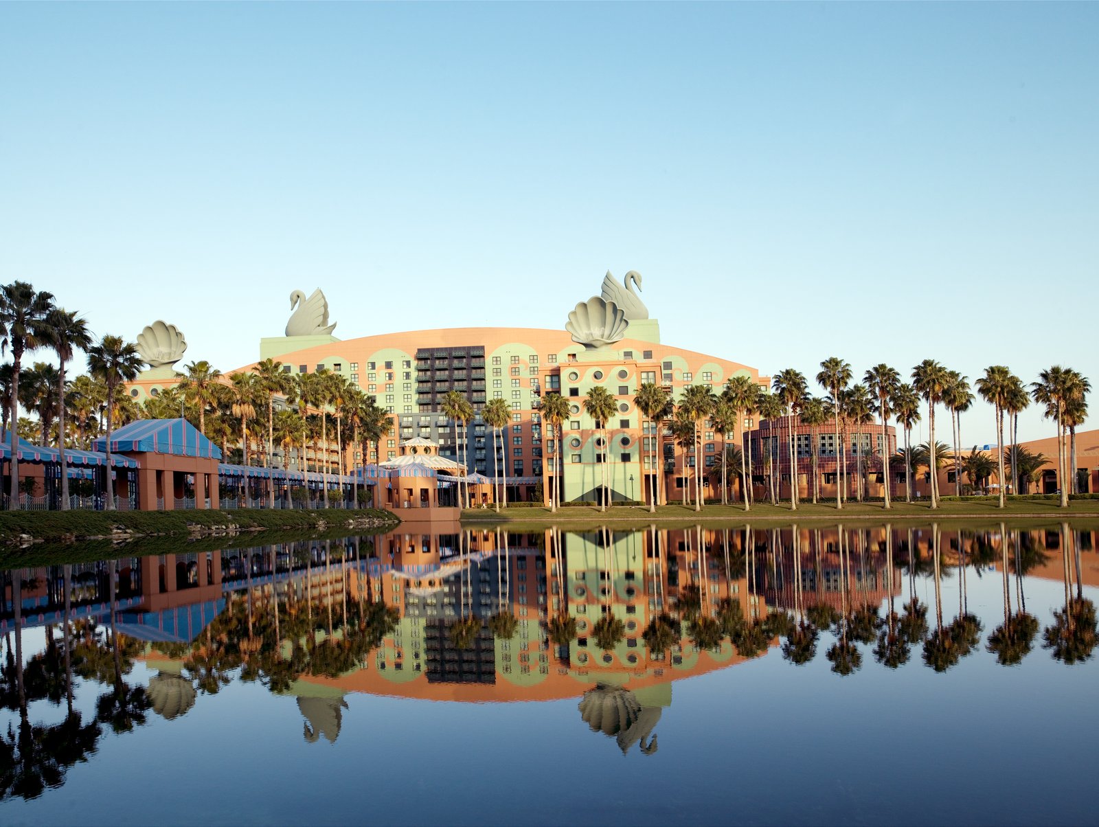 The Swan hotel at Walt Disney World, Florida, reflected in a lake, with palm trees and rooftop swan sculptures.