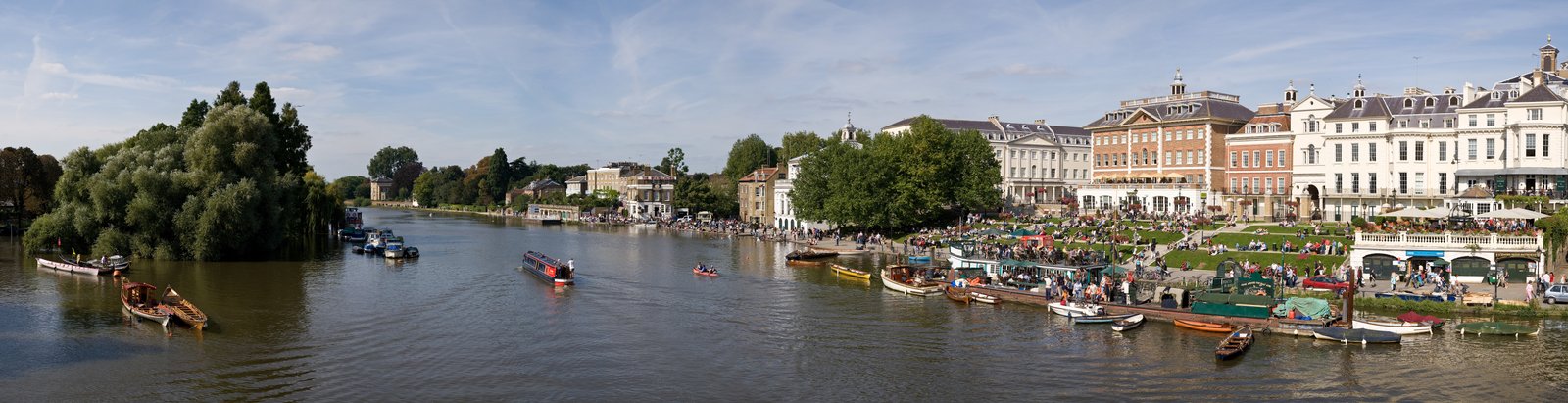 A panorama of Richmond Riverside in London from across the Thames, with boats on the river and Quinlan Terry's terraces along the bank.