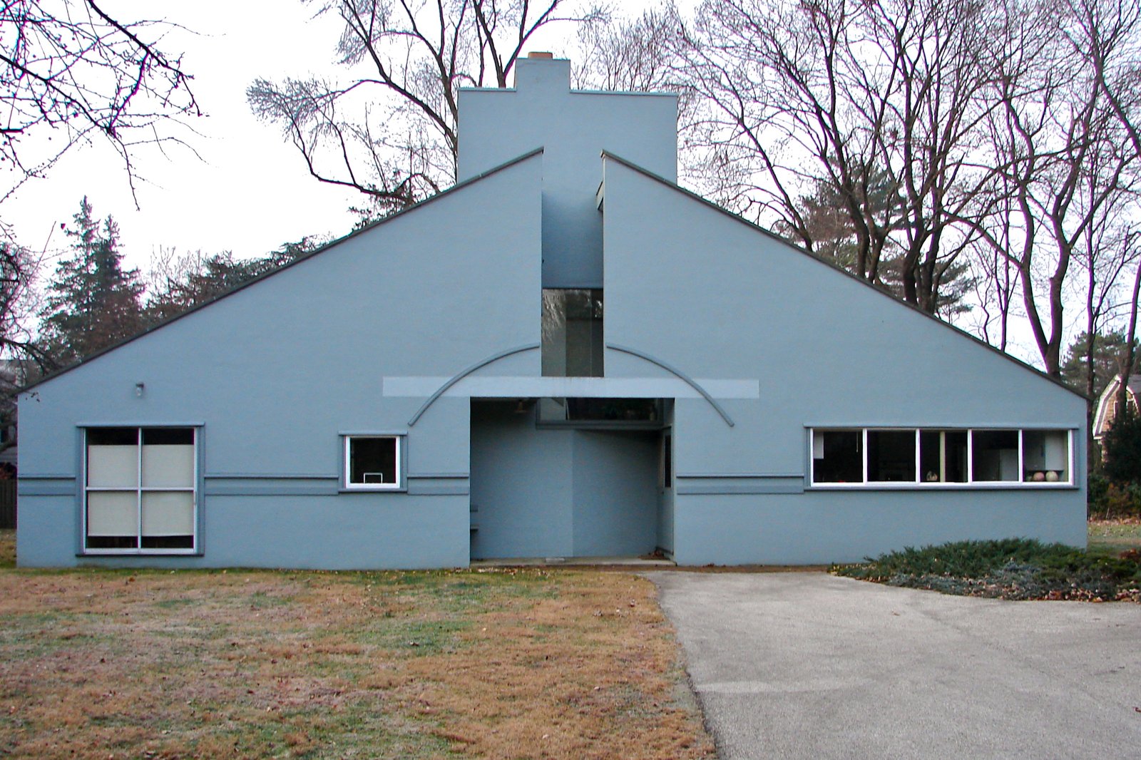 The pale blue front facade of the Vanna Venturi House in Philadelphia, with its large split gable and central entrance.