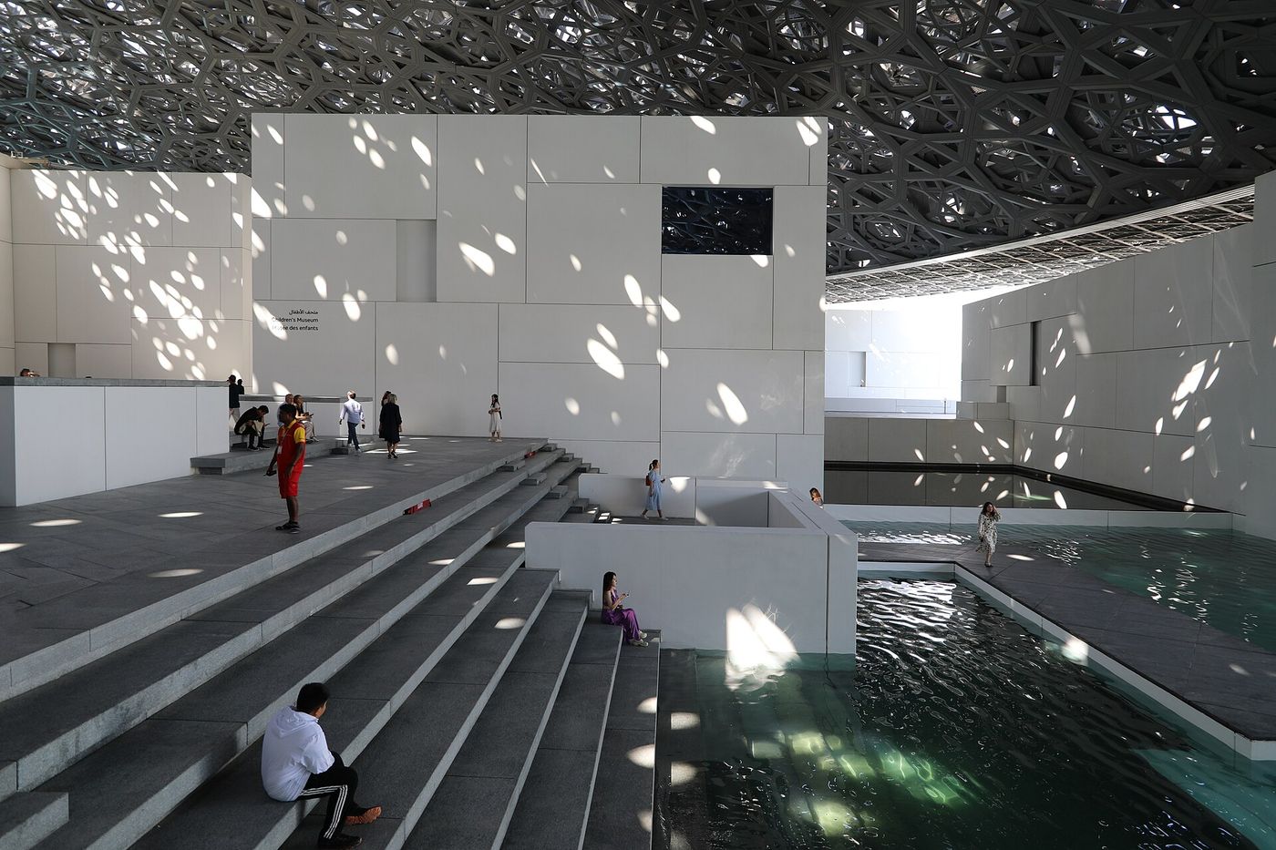 Interior under the dome of Louvre Abu Dhabi, where light filters through the layered dome