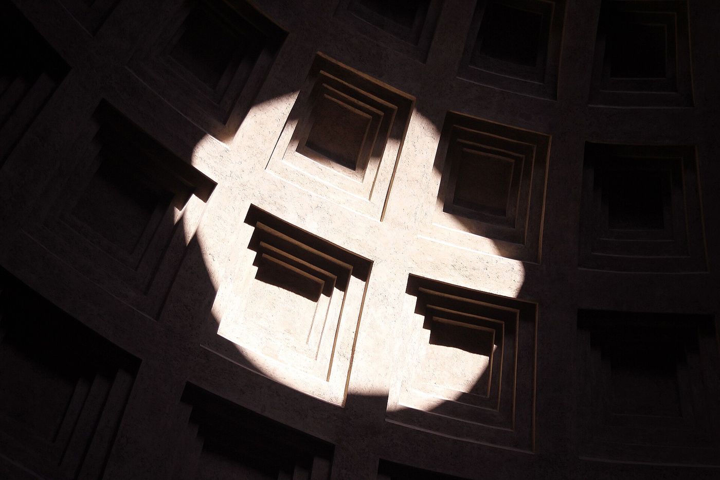 The oculus at the top of the Pantheon dome in Rome, with a shaft of daylight entering the rotunda