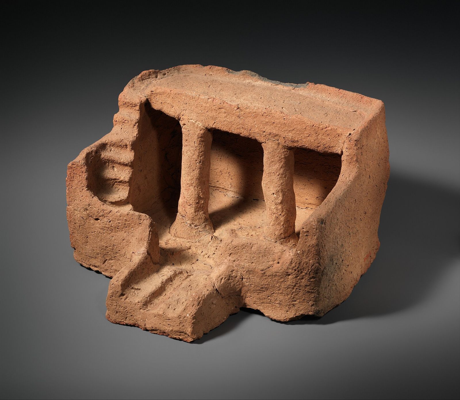 An ancient Egyptian limestone model of a house, with columns and a roof stair