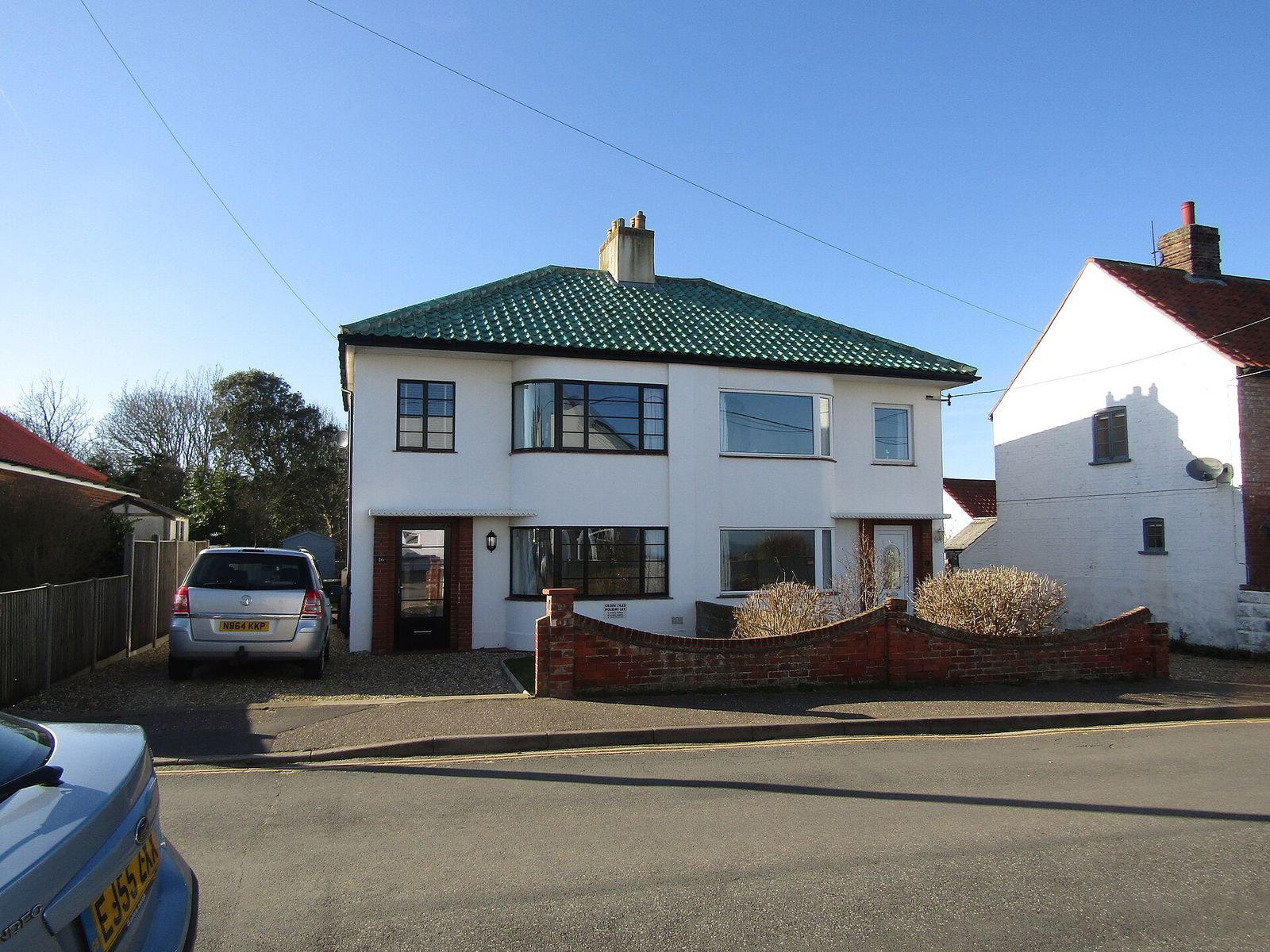 A 1930s art deco semi-detached house in Norfolk, white-rendered with a green-tiled roof