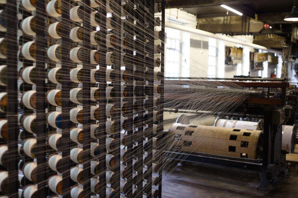 Yarn-spinning machinery at Quarry Bank Mill: rows of bobbins and line shafting in the mill's working interior