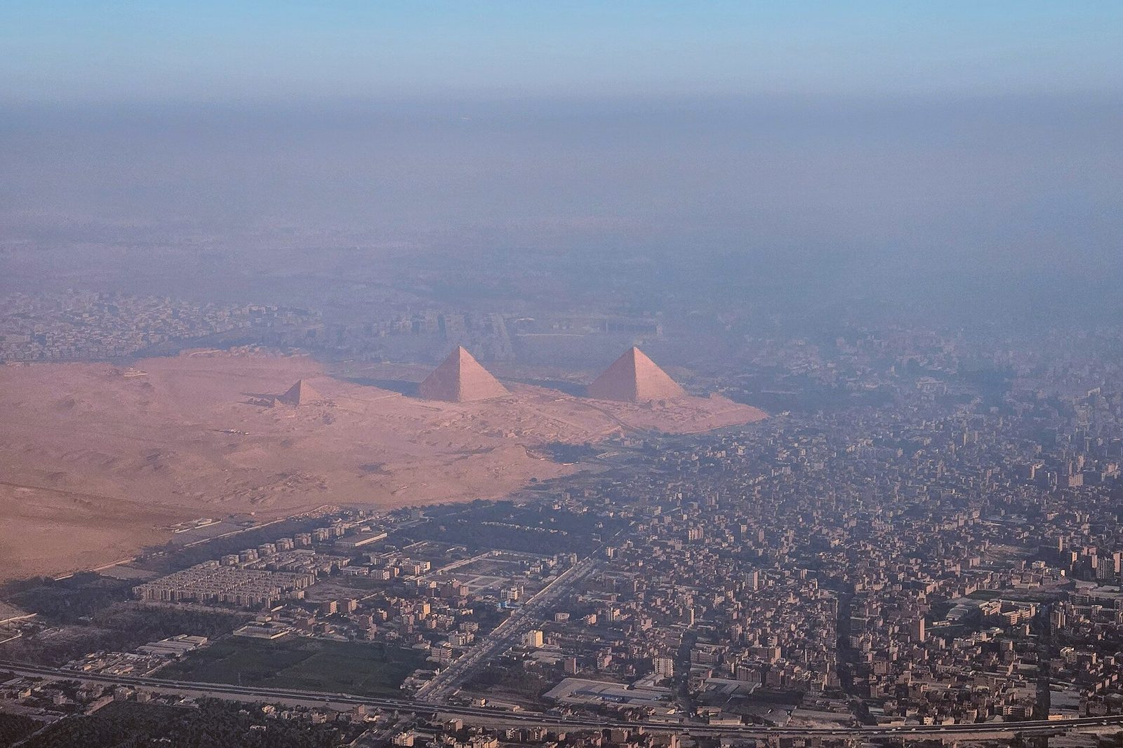 The Giza plateau from the air: the three great pyramids at the desert's edge, with the modern city spread below